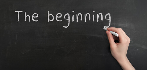 A woman's hand write text the beginning with chalk on chalkboard