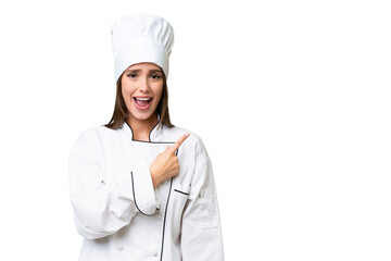 Young chef caucasian woman over isolated background surprised and pointing side
