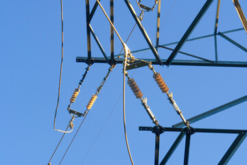 Steel mast of a high-voltage electric pole against the blue sky. Power transmission line. Close-up