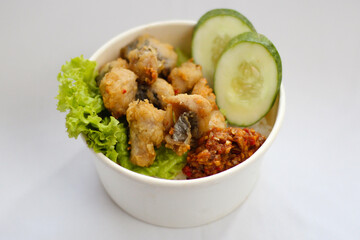 A bowl of food with Bandeng fish vegetable and cucumber slice on top