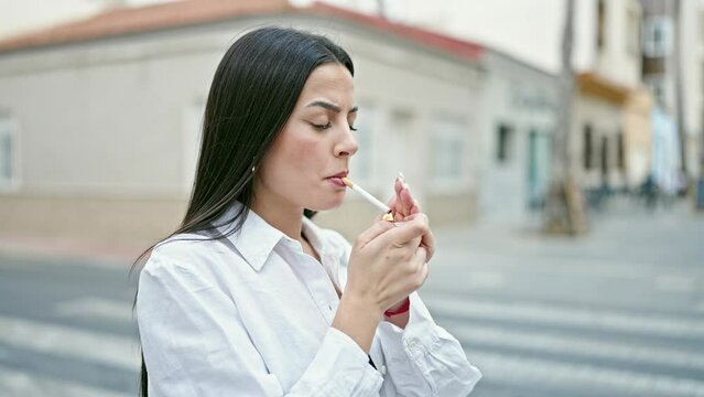 Young beautiful hispanic woman smoking at street