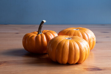 Small orange pumpkins on wooden table background. Front view of three small pumpkins