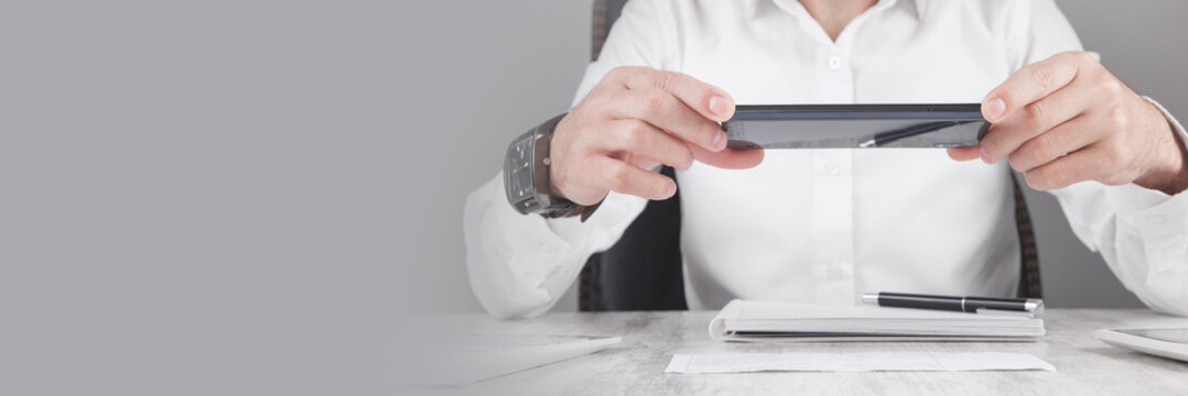 Businessman taking photo of document with smartphone.