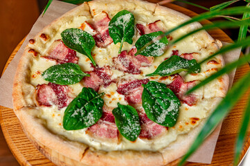 Tasty and big pizza with bacon and fresh salad