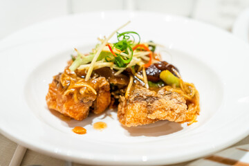 Crispy Fish with Ginger topped with chili sauce Placed on a white plate looks appetizing. in a Thai restaurant