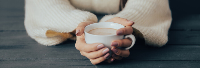 Young woman holding a cup of coffee in her hand