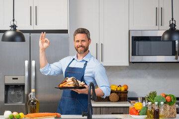 Man in cook apron cooking seafood crab and shrimp, salmon and lobster in kitchen. Happy chef in cook apron cooking seafood. Cook in chef apron on kitchen with salmon fillet. Salmon recipes.