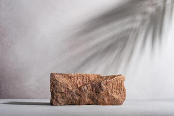 Stone podium for product display with palm leaves shadow on background