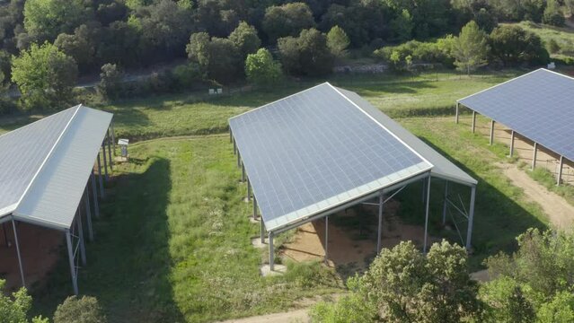 Aerial shot that revolves around a farm of photovoltaic panels on barn roofs
