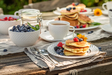 Delicious and homemade american pancakes served with coffee in garden.