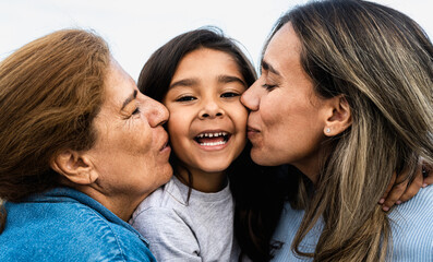 Happy Hispanic family enjoying time together - Child having fun with her mother and grandmother