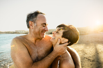 Happy senior couple having a romantic moment on the beach at sunset during summer vacations -...