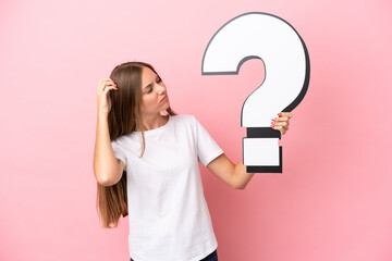 Young Lithuanian woman isolated on pink background holding a question mark icon and having doubts