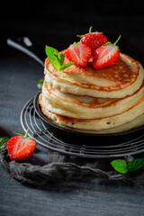 Homemade and sweet american pancakes with powdered sugar and fruits.