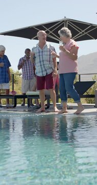 Happy senior diverse people playing at pool and embracing in slow motion