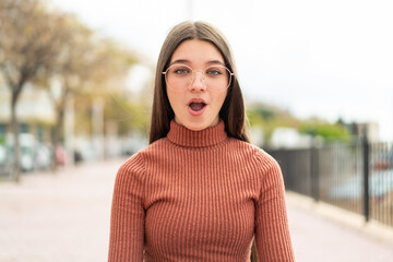 Teenager girl at outdoors With glasses and surprised expression