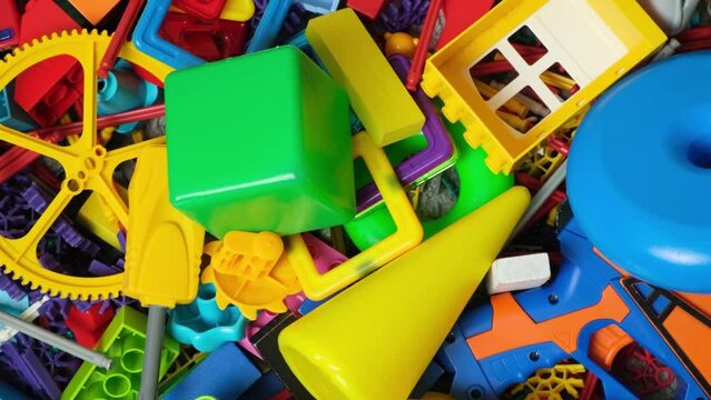 An abundance of toys in the children's room, a lot of plastic multi-colored parts from designers, spare parts for toys, figurines and cubes.
