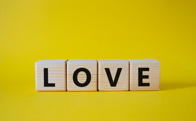 Love symbol. Concept word Love on wooden cubes. Beautiful yellow background. Business and Love concept. Copy space.