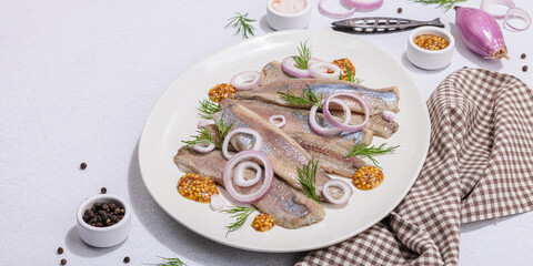 Salted herring with dijon mustard, dill and red onion rings on white stone background