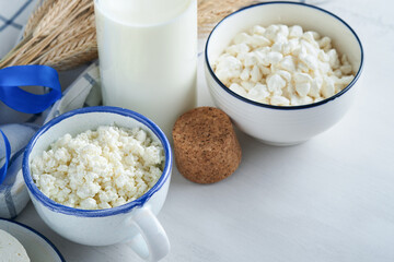 Shavuot jewish holiday celebration. Kosher fresh dairy products milk and cheese, ripe wheat, cream on white wooden background. Dairy products over white wooden background. Shavuot concept. Top view.