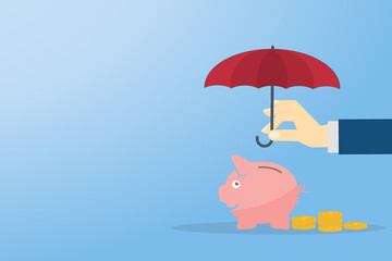 Hand holding umbrella over piggy bank with coins. 