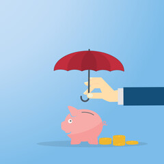 Hand holding umbrella over piggy bank with coins. 