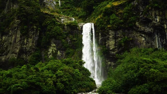 Iconic waterfall from steep rocky cliff in Milford Sound, motion view