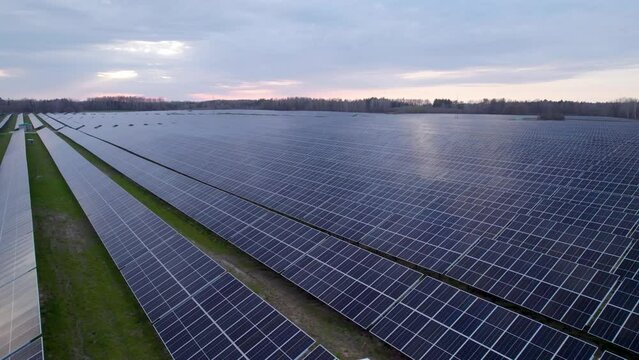 Big solar farm with long rows of PV panels, drone view on overcast day