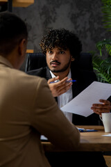 The director of a financial company discusses with his employee the financial statements of the company. A young Indian businessman is discussing new ways to attract investment with his business