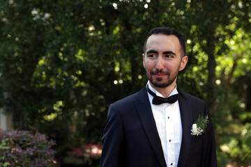 Groom in suits posing in front of a blurry green background