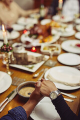 Prayer, dinner and hand holding with family at table in dining room for holiday, food or praying worship. Celebration, support or gratitude with closeup of people at home for kindness, party and love