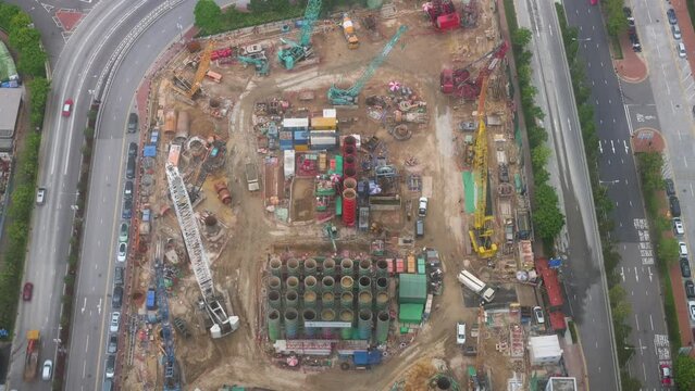 Bird's eye view of a large construction site and engineering equipment such as cranes and metal girders working at a redevelopment commercial project.
