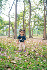 Beautiful asian toddler girl playing on green grass in city park morning sunrise