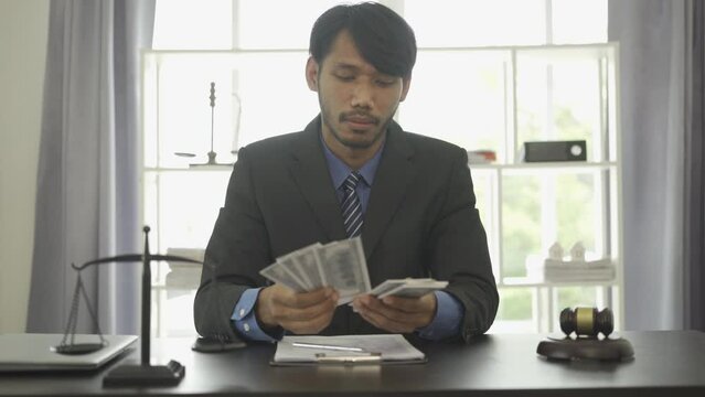 Corrupt lawyer counting money hiding bribes in shirt forgery documents judge counting cash against judge background at workplace. 4k movie