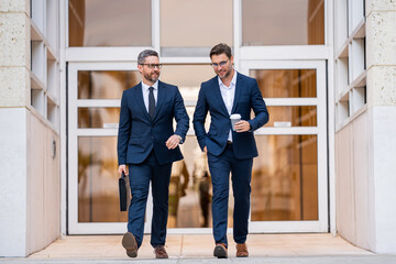 Businessmen walk in the street. Two businessmen walking and talking at office building. Two...