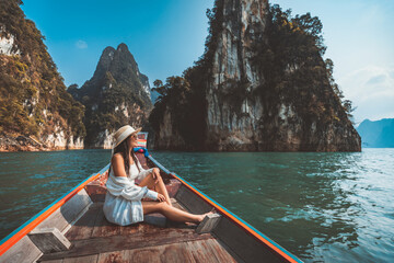 Traveler asian woman relax and travel on Thai longtail boat in Ratchaprapha Dam at Khao Sok...