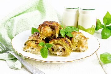 Rolls of zucchini with meat in plate on light board