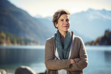 Portrait of mature woman with arms crossed on lake shore in autumn