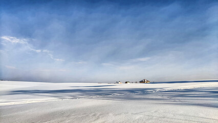 View of winter landscape with snowy fields and blue sky in cold day with sun. Freezing lake or river under snow and ice