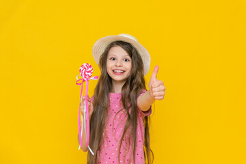 A little sweet tooth in a straw hat with a lollipop on a stick. A child holds sweets and candies in...
