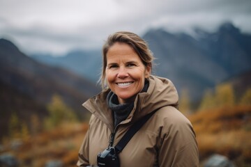 Naklejka premium Portrait of a smiling mature woman with backpack hiking in the mountains