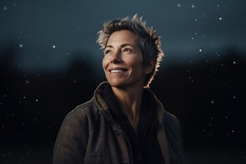 Portrait of a happy mature woman standing outdoors at night in the rain.