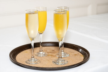 Straight champagne and mixed orange juice mimosas are ready to served to guests on a tray