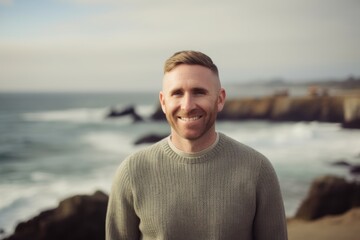 Portrait of smiling man standing by the ocean at the beach on a sunny day