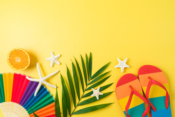 LGBTQ pride month beach party background with rainbow flip flops, palm leaf and  paper fan. Top view, flat lay