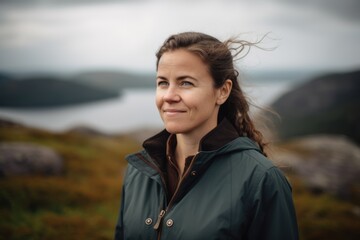 Portrait of a beautiful young woman in a raincoat on the top of a mountain.