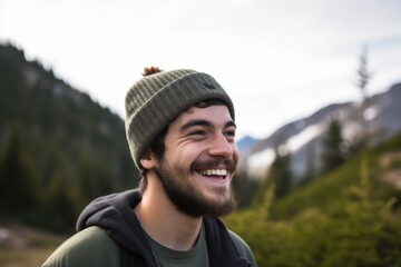 Portrait of a smiling young man with hat and backpack in mountains