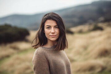 Studio portrait photography of a satisfied woman in her 20s wearing a cozy sweater against a hillside or rolling hills background. Generative AI