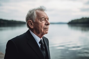 Portrait of an elderly man on the river bank. Portrait of an elderly man in a black suit.