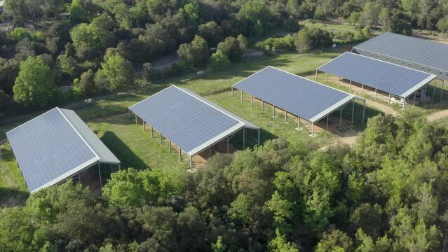 Aerial shot in rotation around a solar panel farm in the forest, in the French countryside